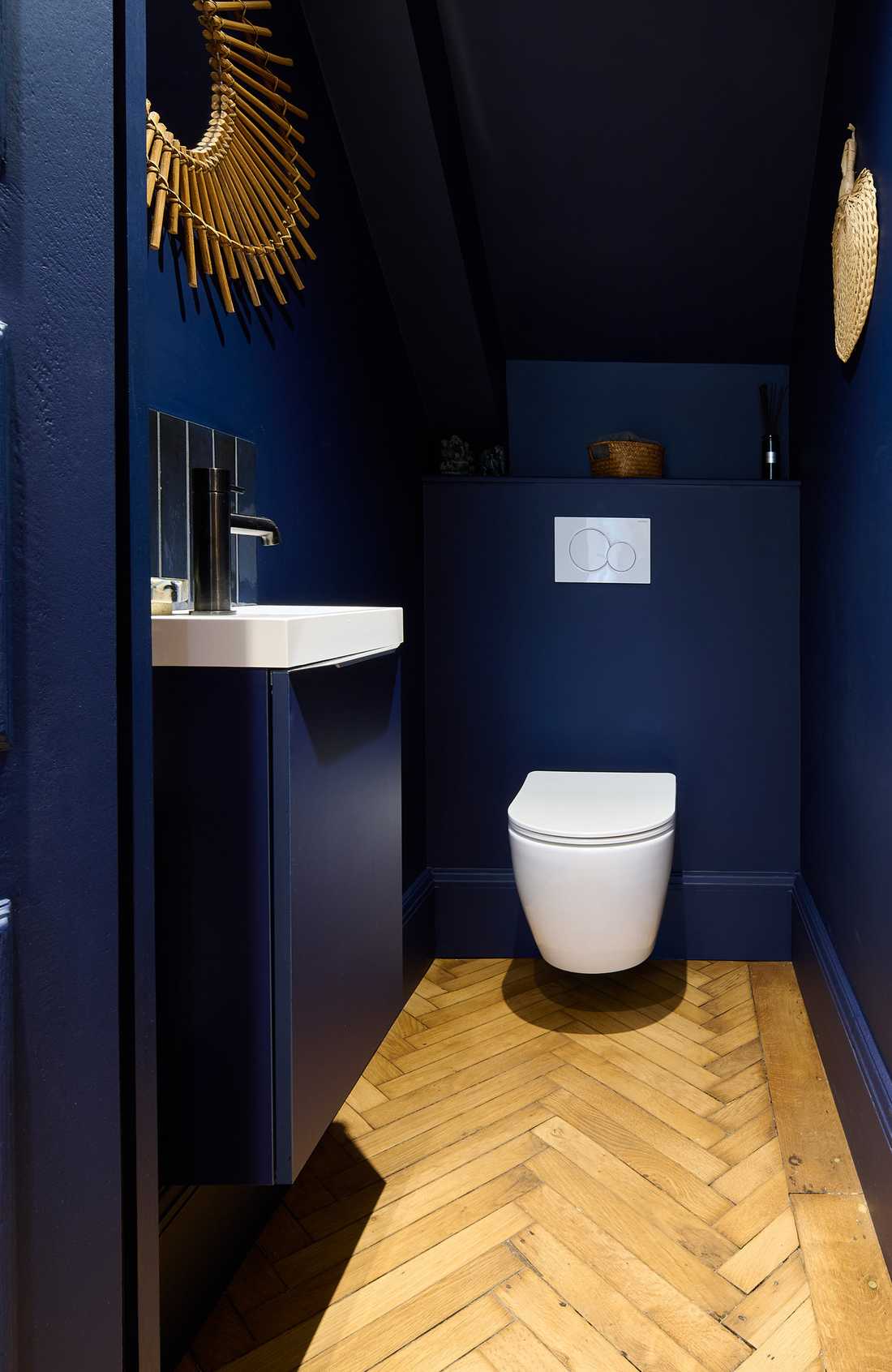 WC avec mur bleu foncé et parquet motif bâton rompu
